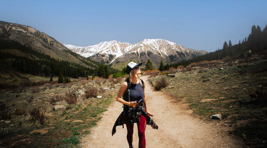 Women hiking away from snow capped mountains.