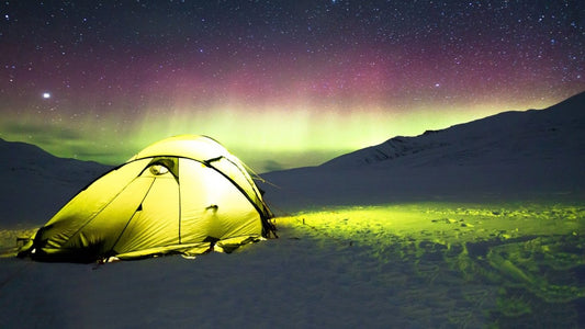 Aurora borealis illuminating the night sky behind a tent.