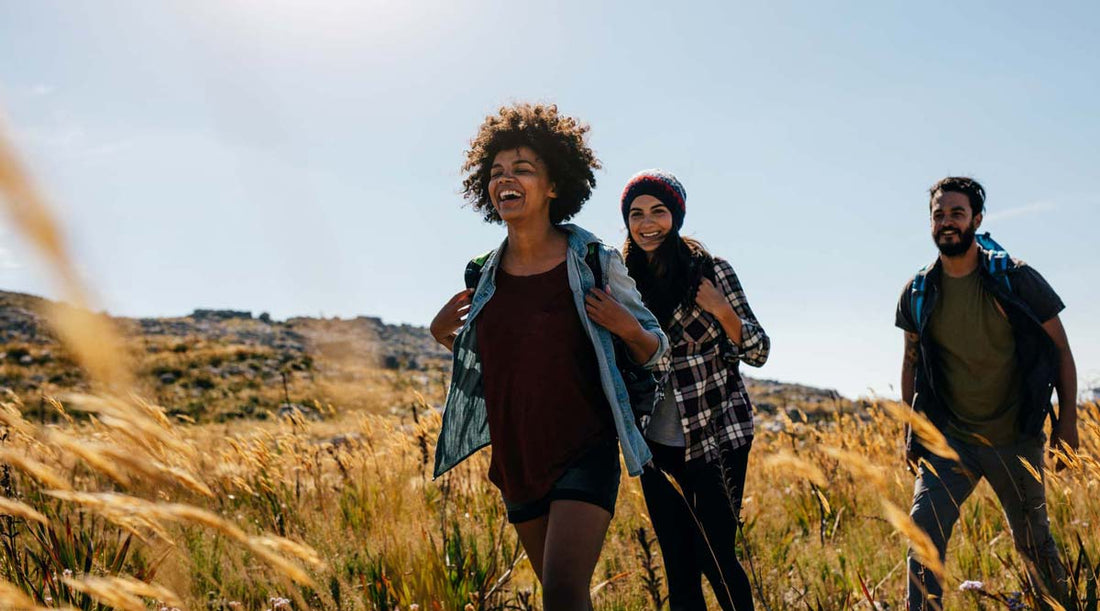 Group of three smiling hikers enjoying a nature hike on a sunny day.