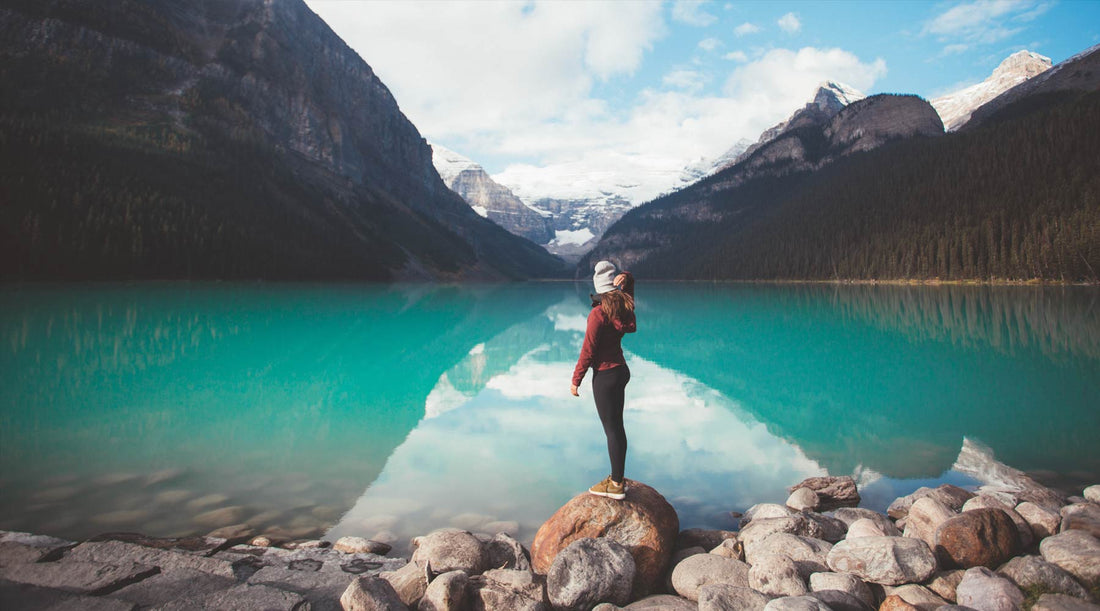 Hiker standing on edge glacial mountain lake.