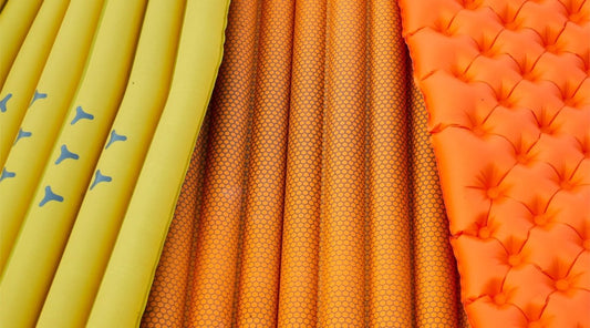 3 inflatable sleeping pads fanned out on the ground viewed from above.