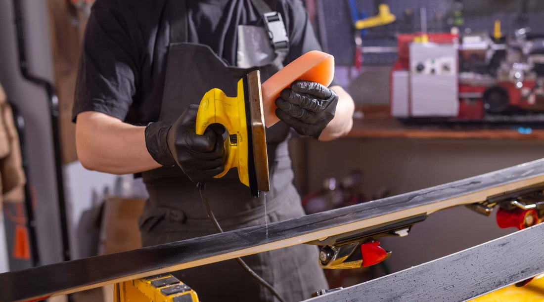 Man in workshop applying hot wax to a ski. 