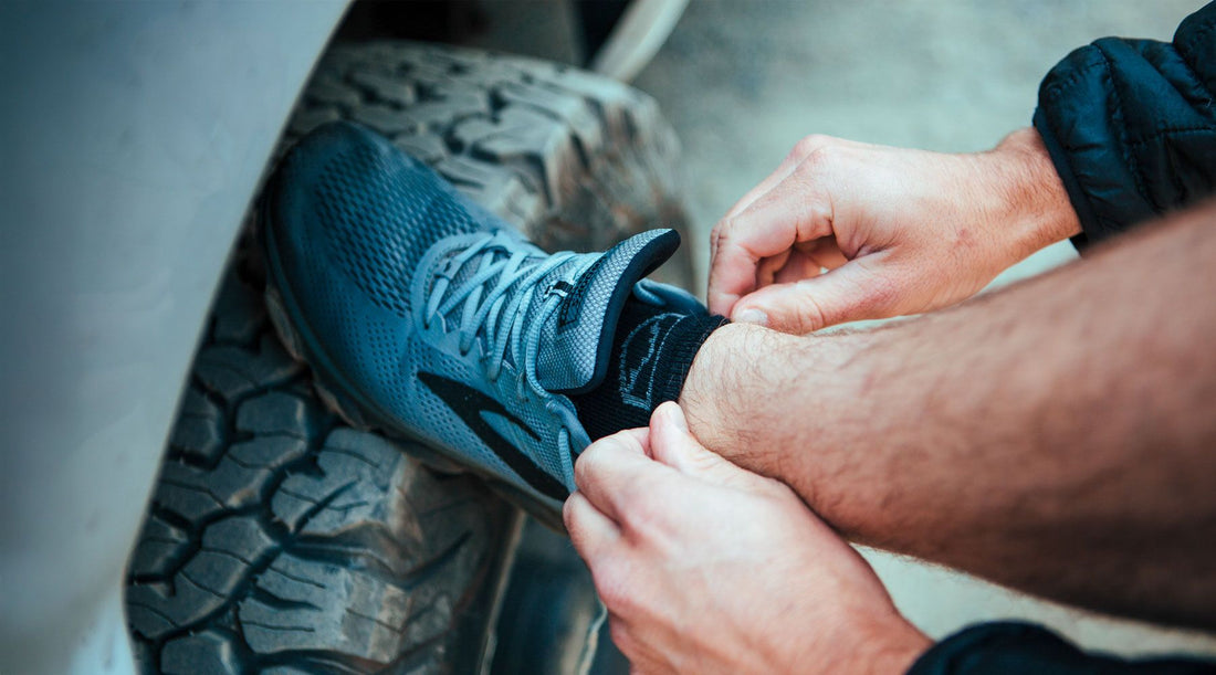 Runner wearing Cloudline merino wool running socks tying shoe laces before a run.