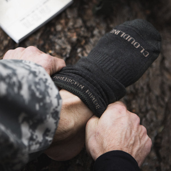 Man pulling on a pair of Cloudline socks showing American Made knit inside the cuff. 