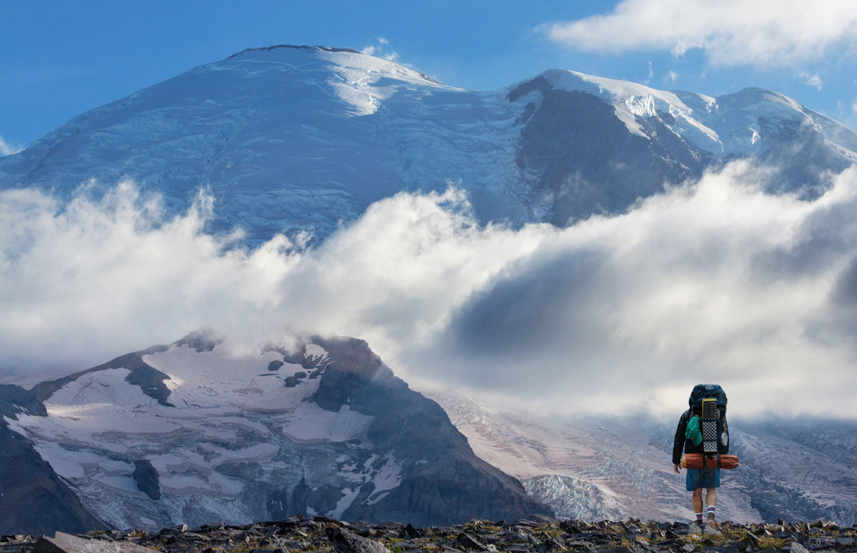 Backpacker wearing Cloudline socks looking at Mt Rainier and the cloudline across it.