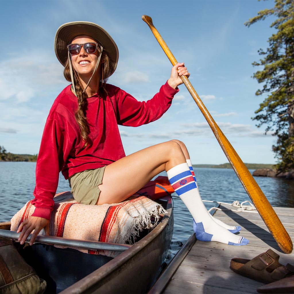Women wearing Cloudline compression socks sitting in canoe with feet on dock.