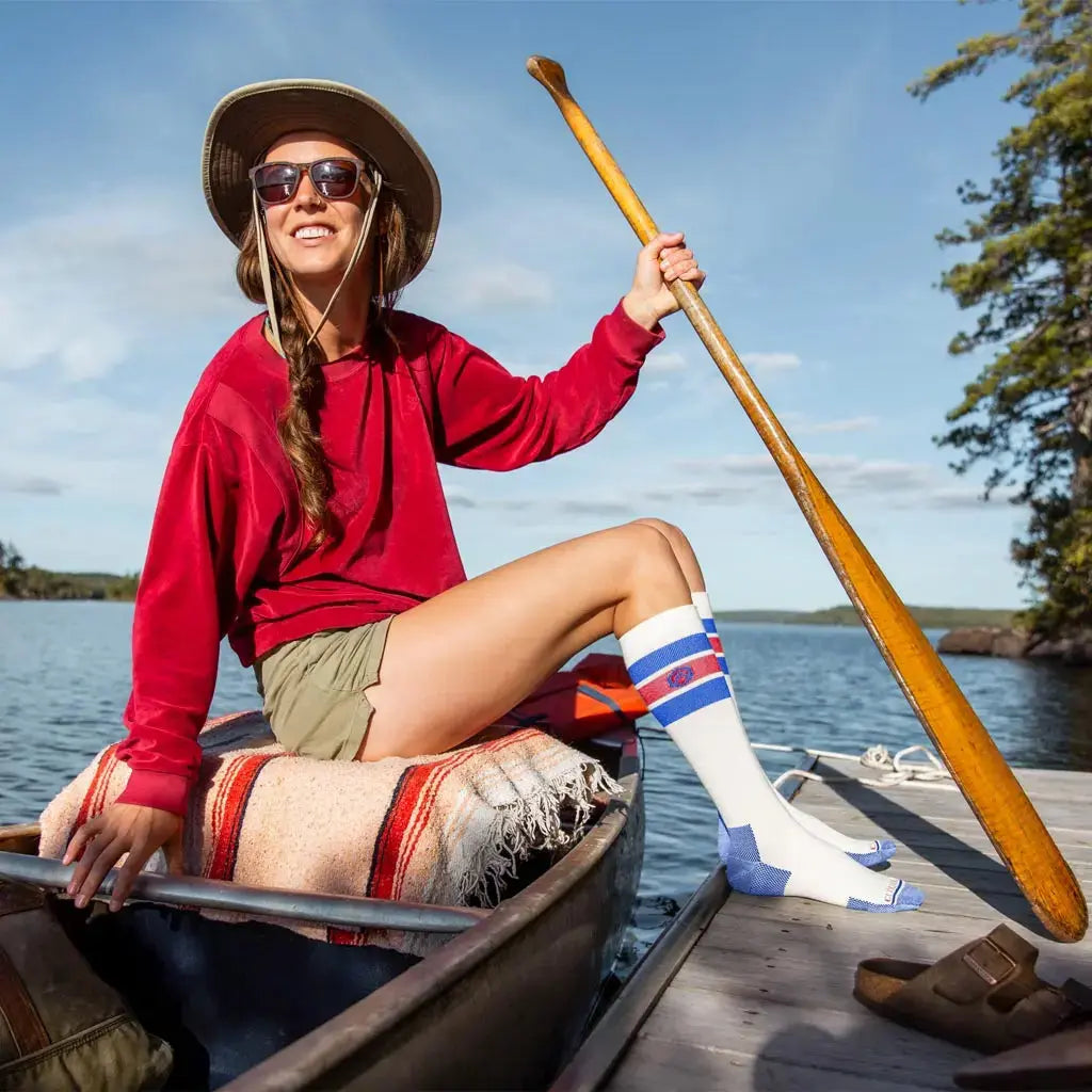 Women wearing Cloudline merino wool compression socks sitting in canoe with feet on dock.