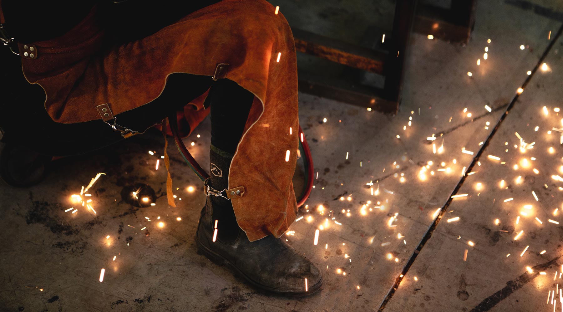 Welder wearing Cloudline work socks while welding with sparks flying. 