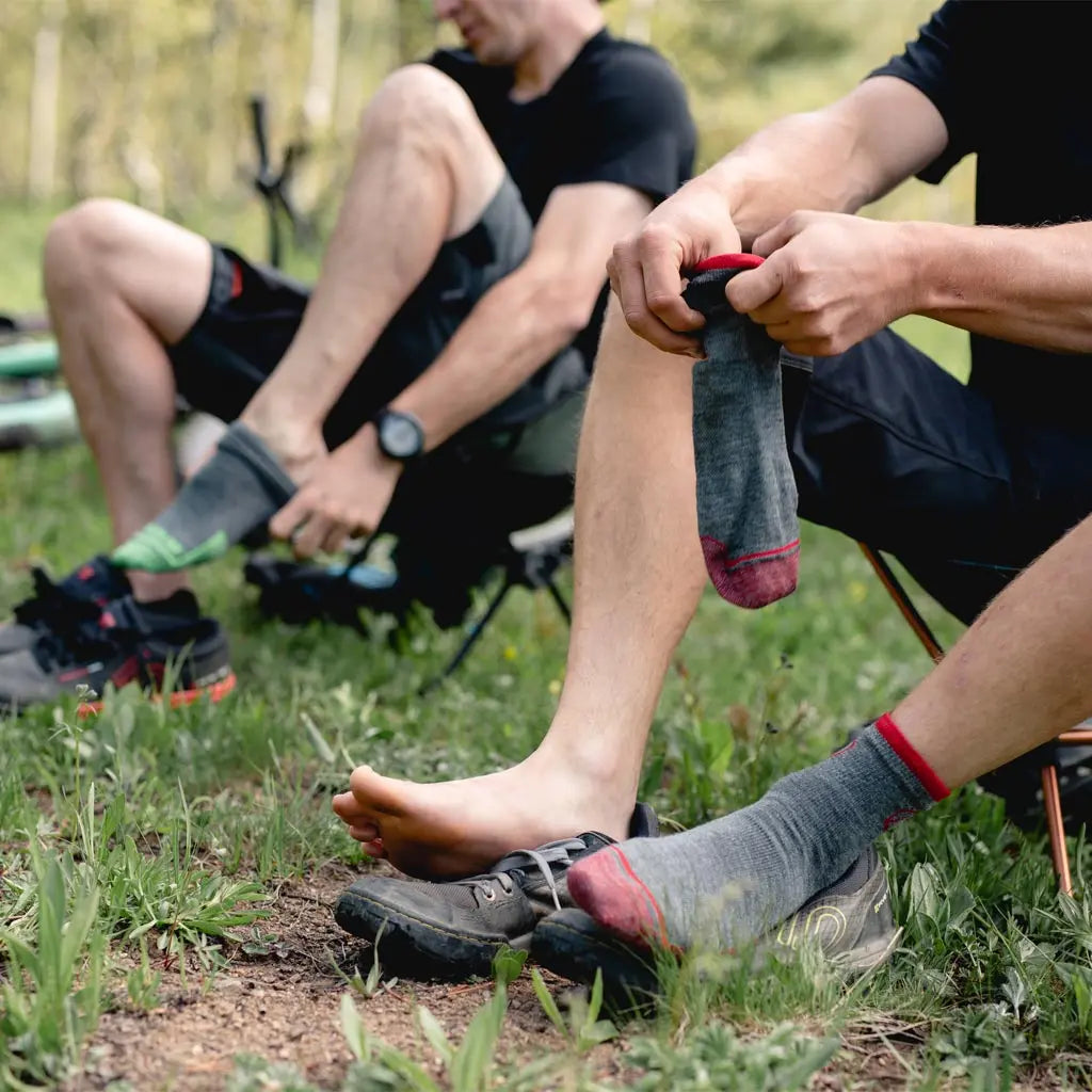 Two guys sitting in camp chairs putting on cloudline 1/4 top merino wool socks.