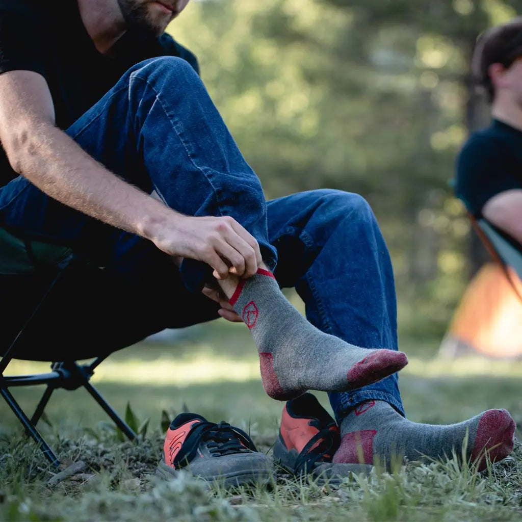 Camper sitting in camp chair pulling on his Cloudline 1/4 top merino wool socks.