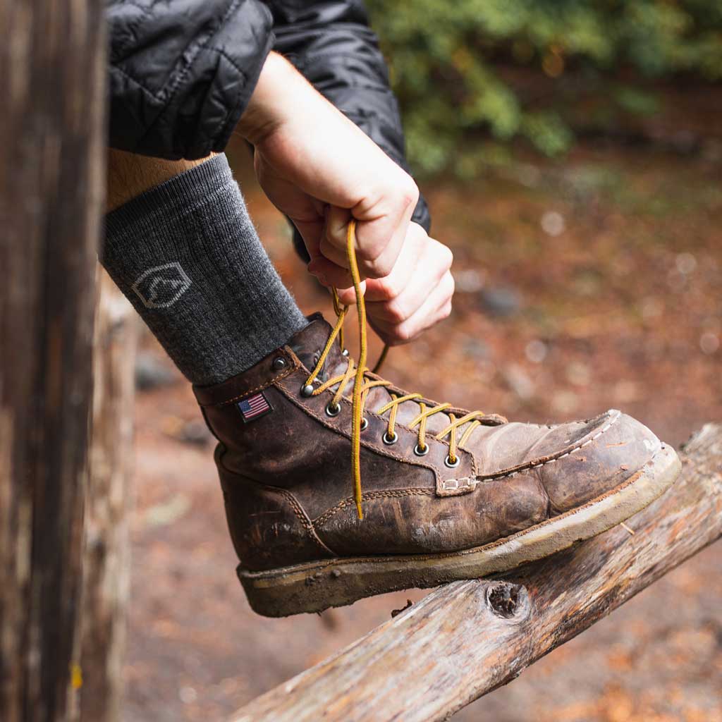 Hiker wearing Cloudline merino wool hiking socks and tying boot laces before hike.