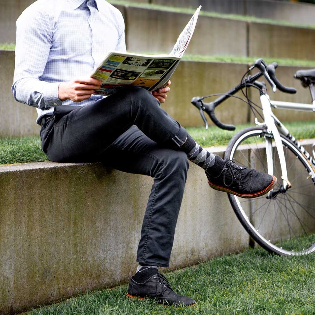 Office Worker wearing Cloudline Active Dress Socks sitting on ledge reading paper.