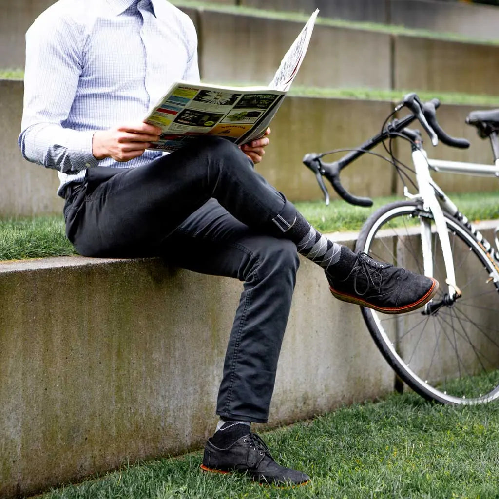 Office Worker wearing Cloudline Merino Wool Active Dress Socks sitting on ledge reading paper.