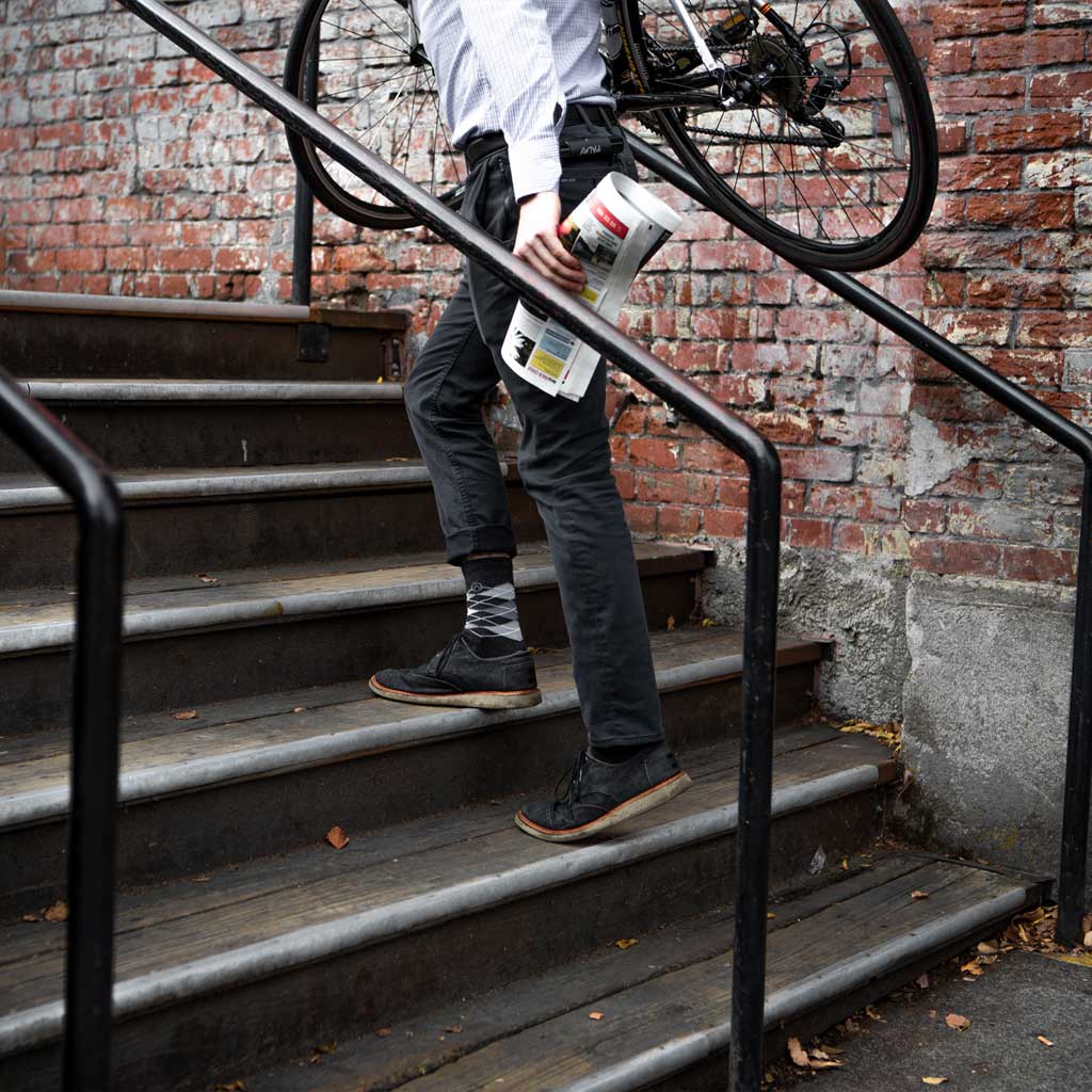 Office worker wearing Cloudline dress socks and caring bicycle up stairs. 