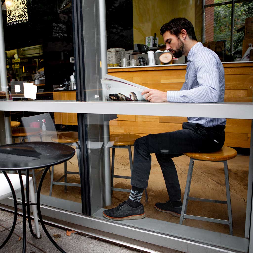 Man in business casual attire and Cloudline Active Dress Socks, sitting in coffee shop reading.