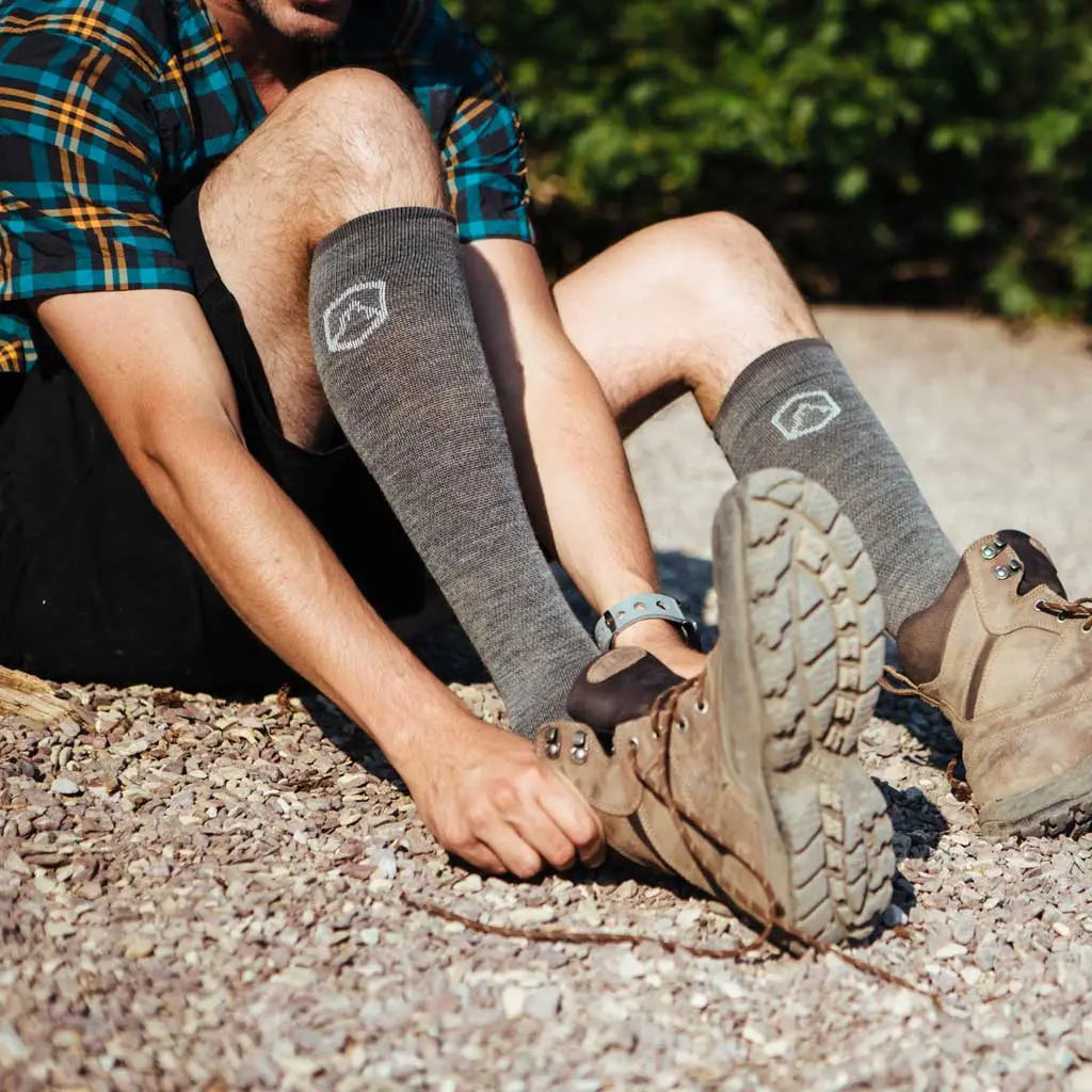 Hiker wearing Cloudline merino wool compression socks putting on leather hiking boots.