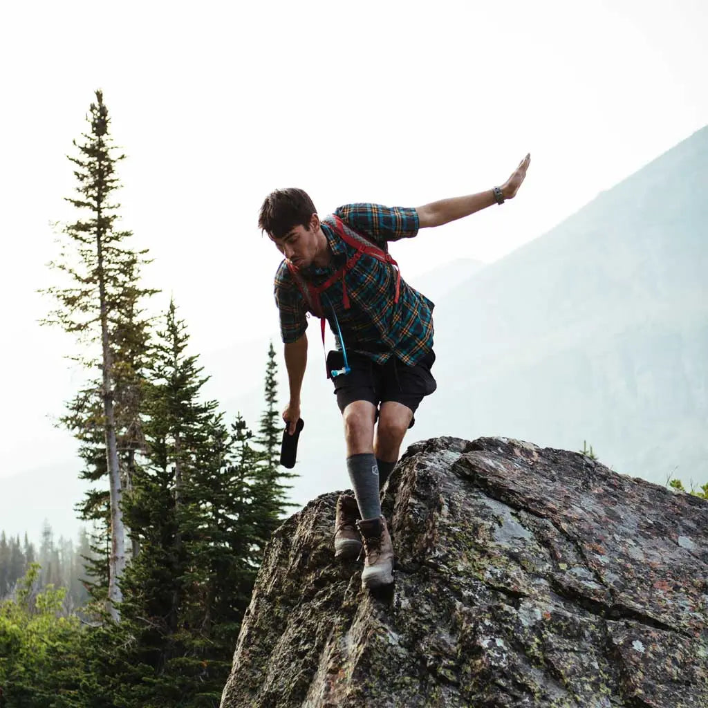 Man climbing down from big rock wearing Cloudline merino wool compression socks.