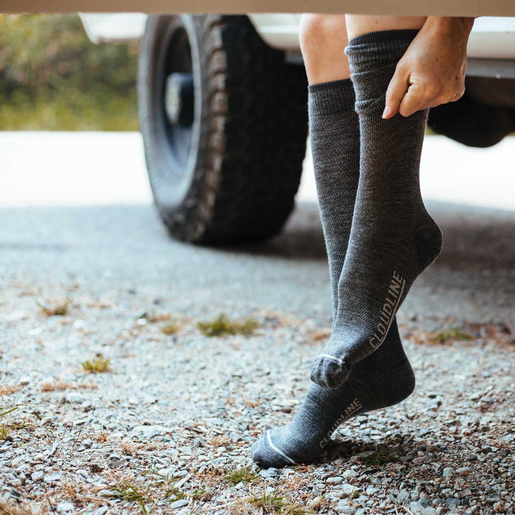 Women sitting in camper van doorway pulling on Cloudline compression socks.