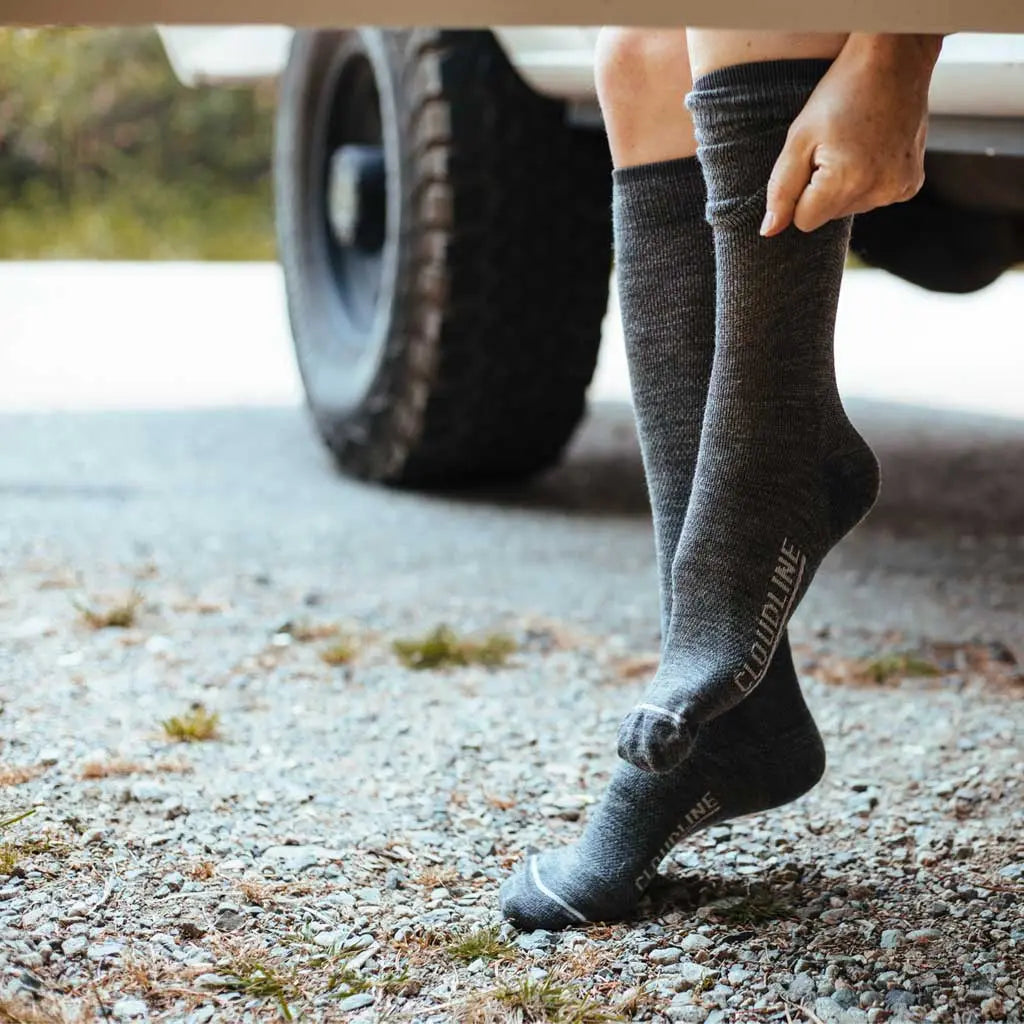 Women sitting in camper van doorway pulling on Cloudline merino wool compression socks.