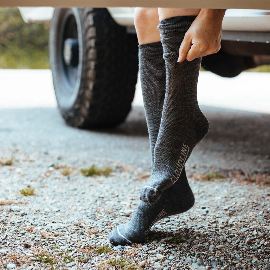 Women sitting in camper van doorway putting on Cloudline compression socks. 