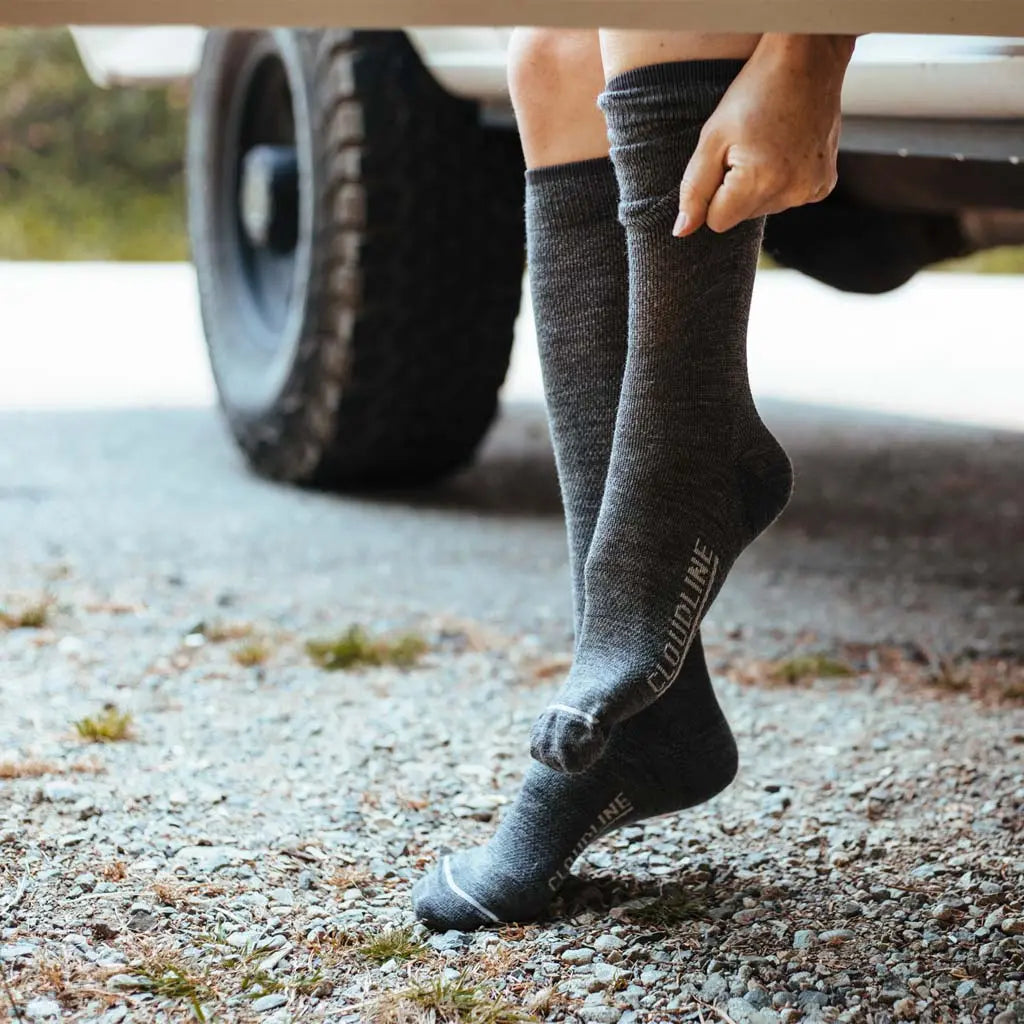 Women sitting in camper van doorway putting on Cloudline merino wool compression socks.