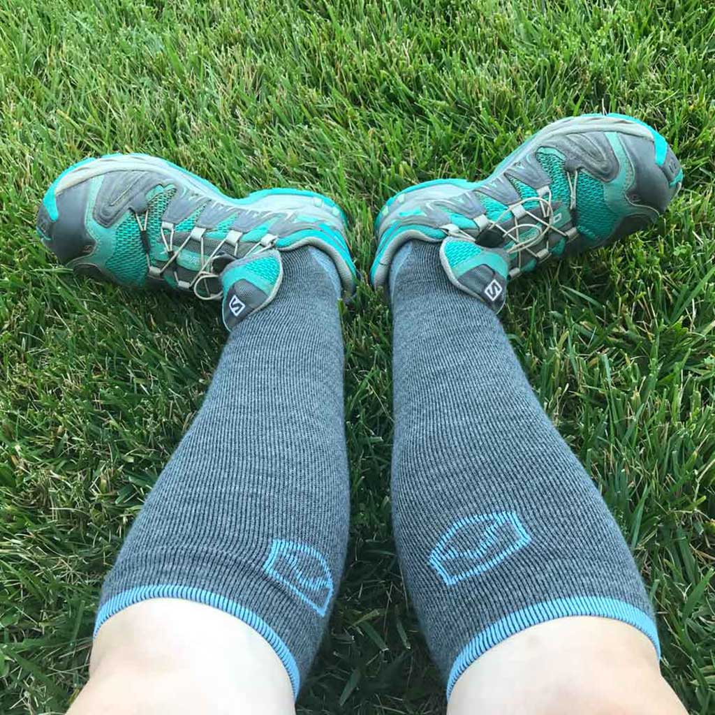 Runner wearing Cloudline merino wool compression socks sitting in grass to stretch post run.