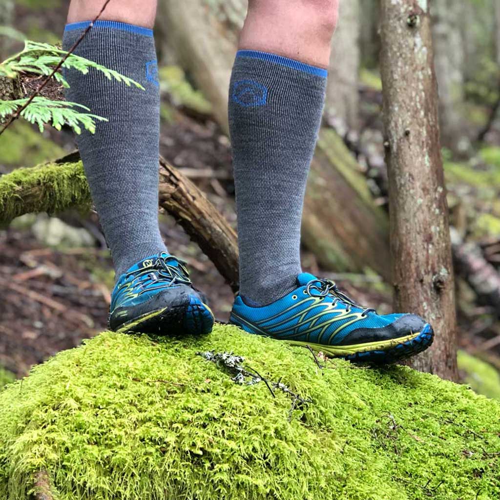 Trail Runner wearing Cloudline merino wool compression socks standing on mossy rock.
