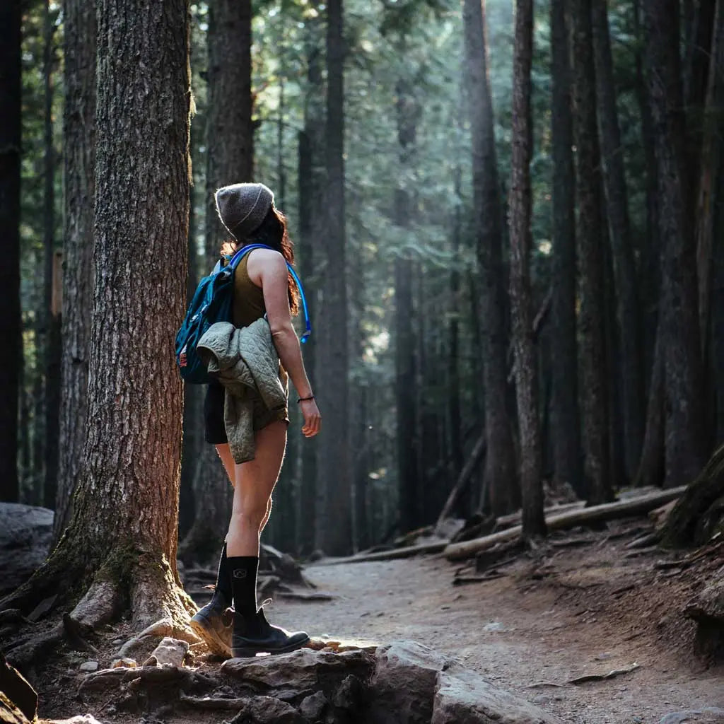 Women wearing Cloudline merino wool compression socks standing on forest trail looking up into the trees.