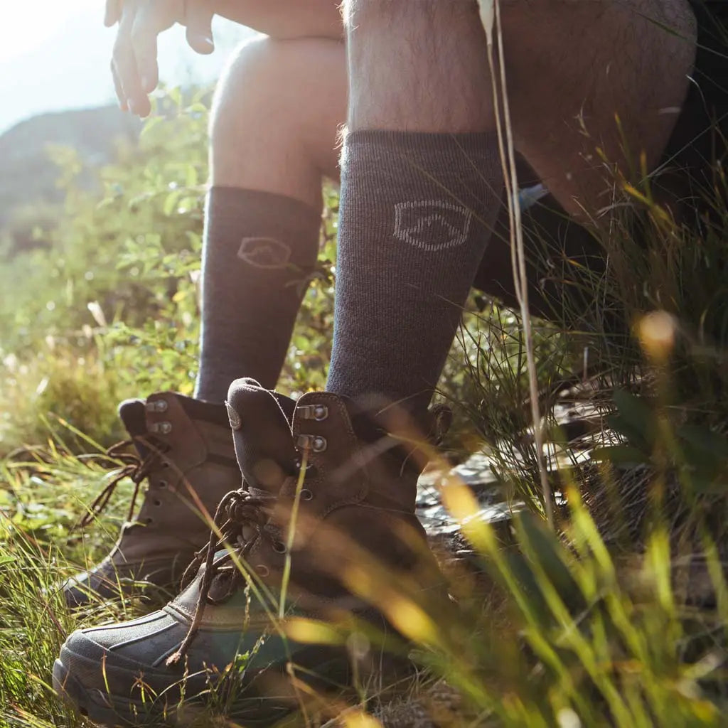 Hiker wearing Cloudline merino wool compression socks taking a break sitting next to trail.