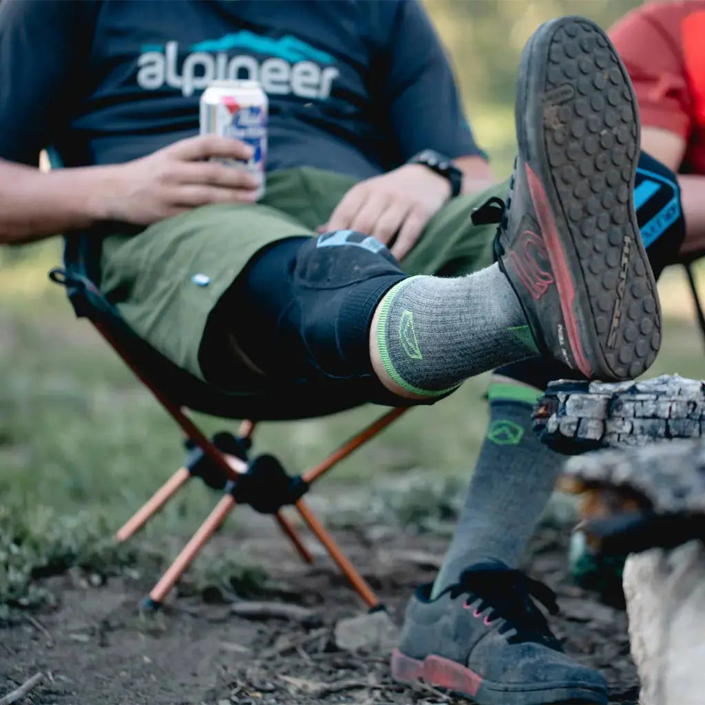Camper sitting next to fire with foot up to show his Cloudline merino wool hiking socks.