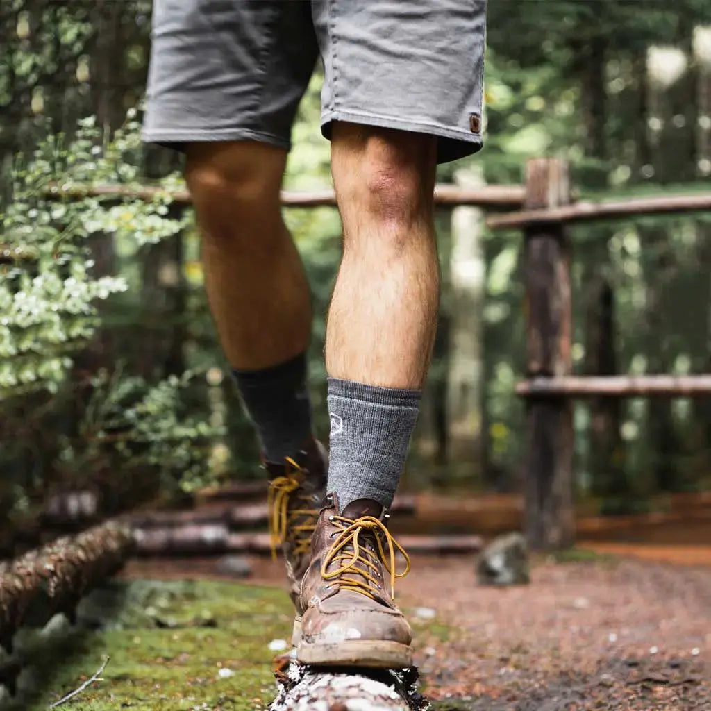 Man wearing Cloudline merino wool hiking socks, walking on fallen log.