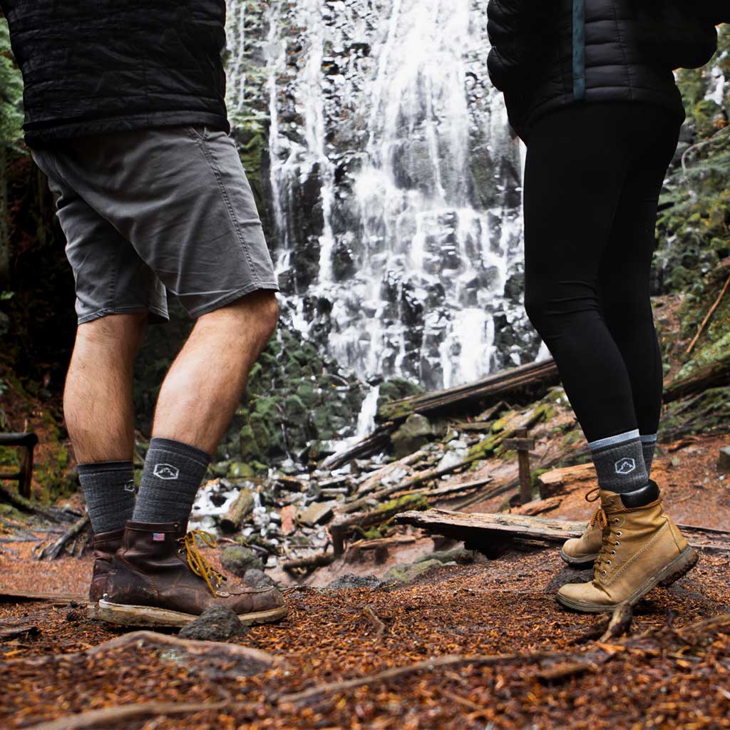 Two hikers wearing Cloudline socks while admiring epic waterfall.
