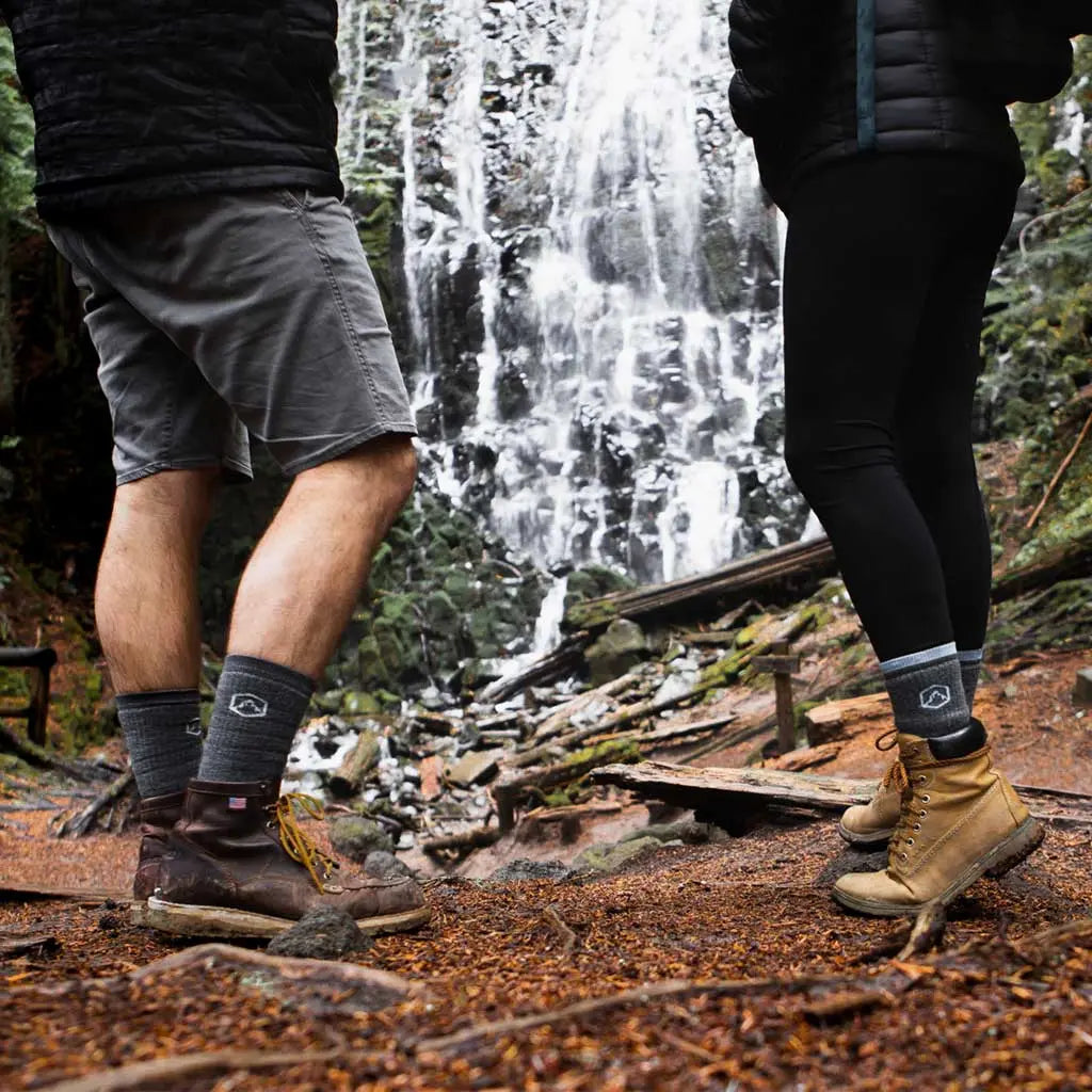 Two hikers wearing Cloudline merino wool hiking socks while admiring epic waterfall.