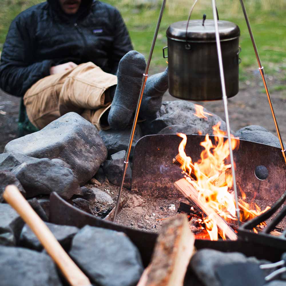 Man sitting by campfire wearing Cloudline merino wool hiking socks.