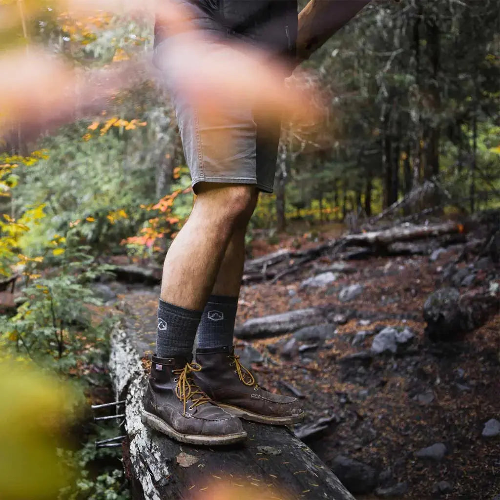 Hiker wearing Cloudline merino wool hiking socks standing on log bridge.