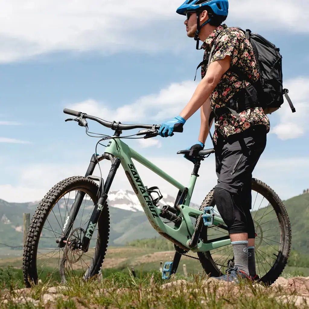 Mountain biker wearing Cloudline merino wool crew socks standing next to mtb with mountains in the background.