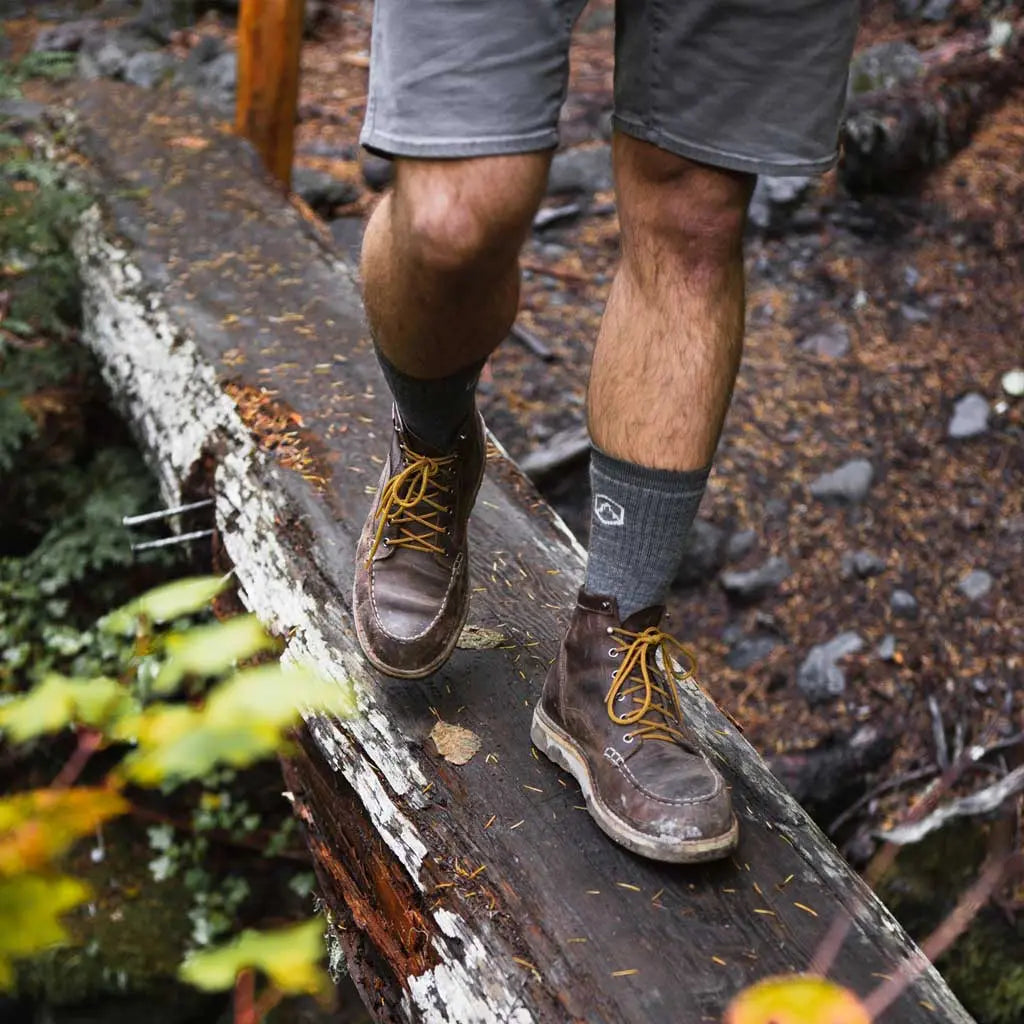 Hiker wearing Cloudline merino wool hiking socks, walking across log bridge.