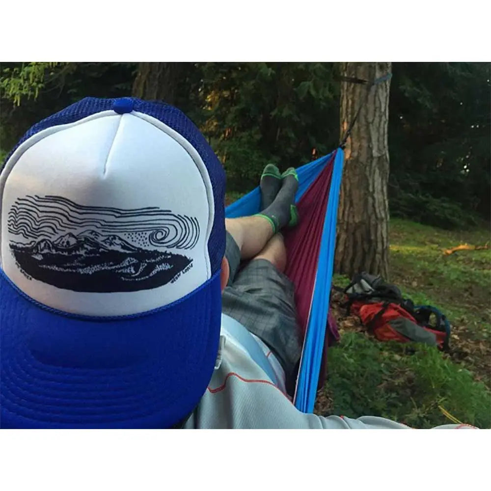Hiker relaxing in hammock wearing Mt Baker hat and Cloudline socks.