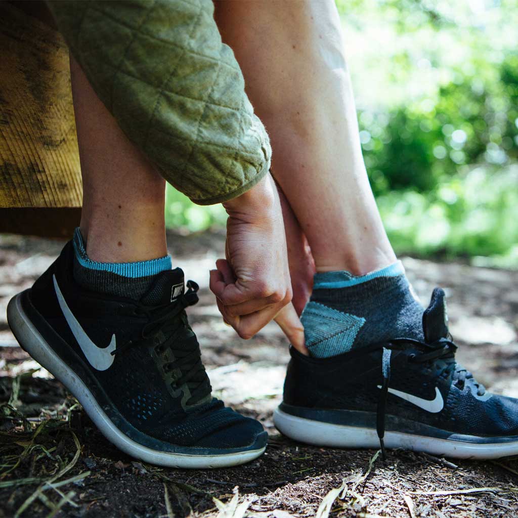 Women wearing Cloudline running socks sliding foot into running shoe. 