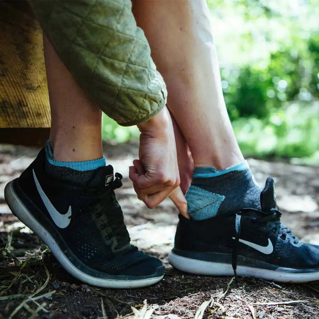 Women wearing Cloudline merino wool running socks sliding foot into running shoe.