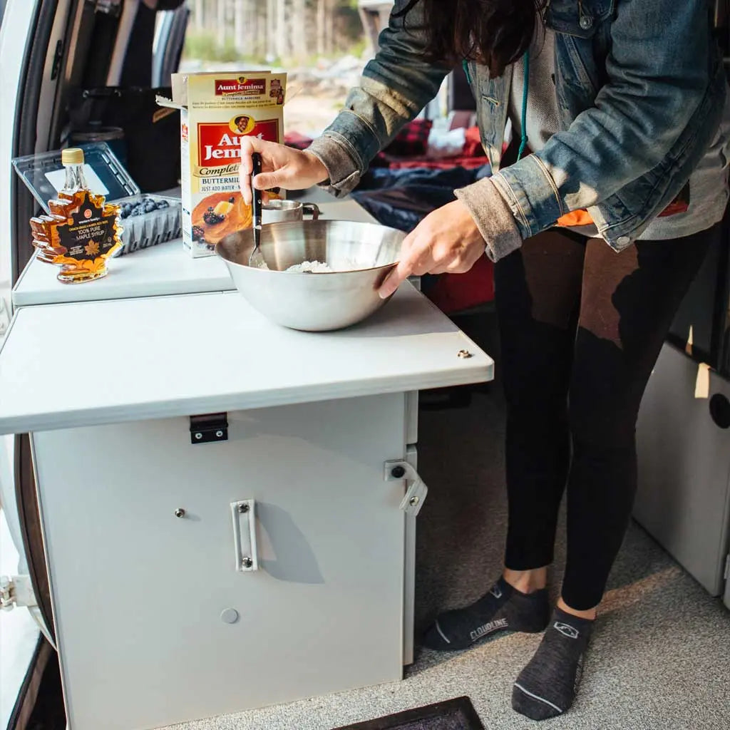 Women making breakfast in camper van wearing Cloudline merino wool running socks and without shoes.