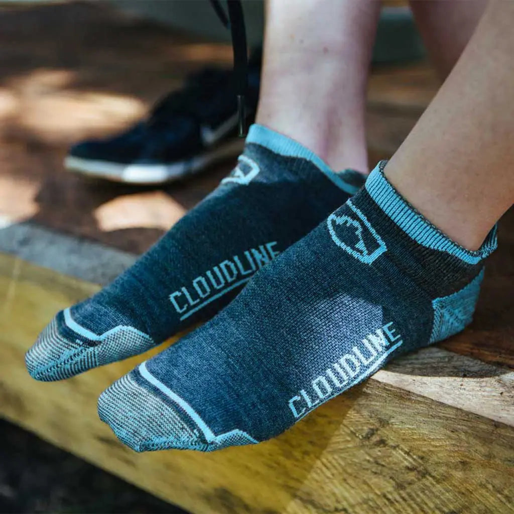 Women wearing Cloudline merino wool running socks sitting on wooden porch with shoes off.