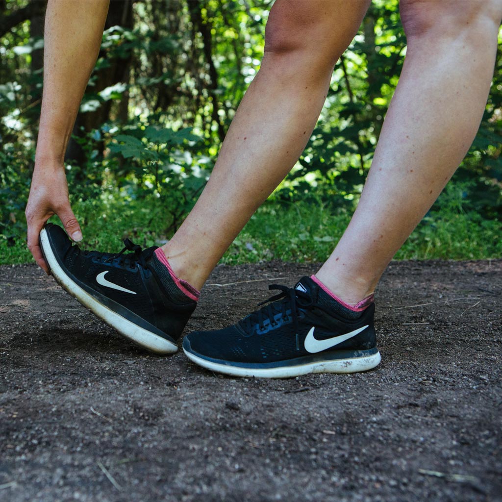 Runner wearing Cloudline no show socks stretching to touch toes. 