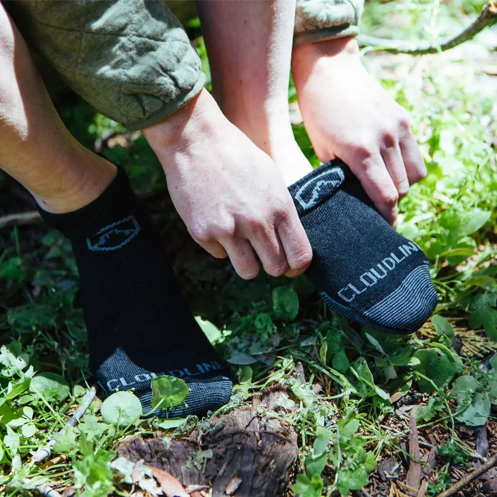 Women pulling on Cloudline merino wool running socks before a trail run.