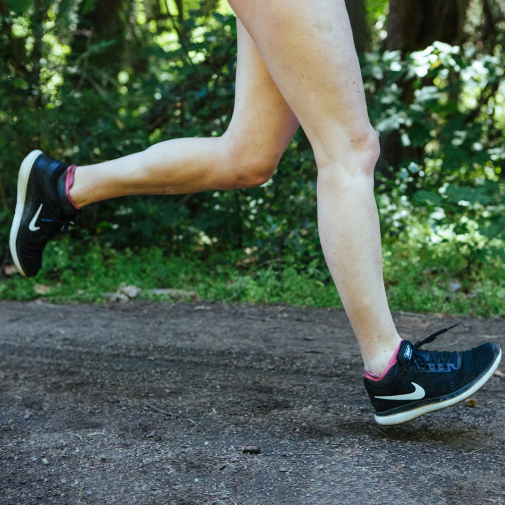 Runner wearing Cloudline running socks mid stride with both feet off the ground.