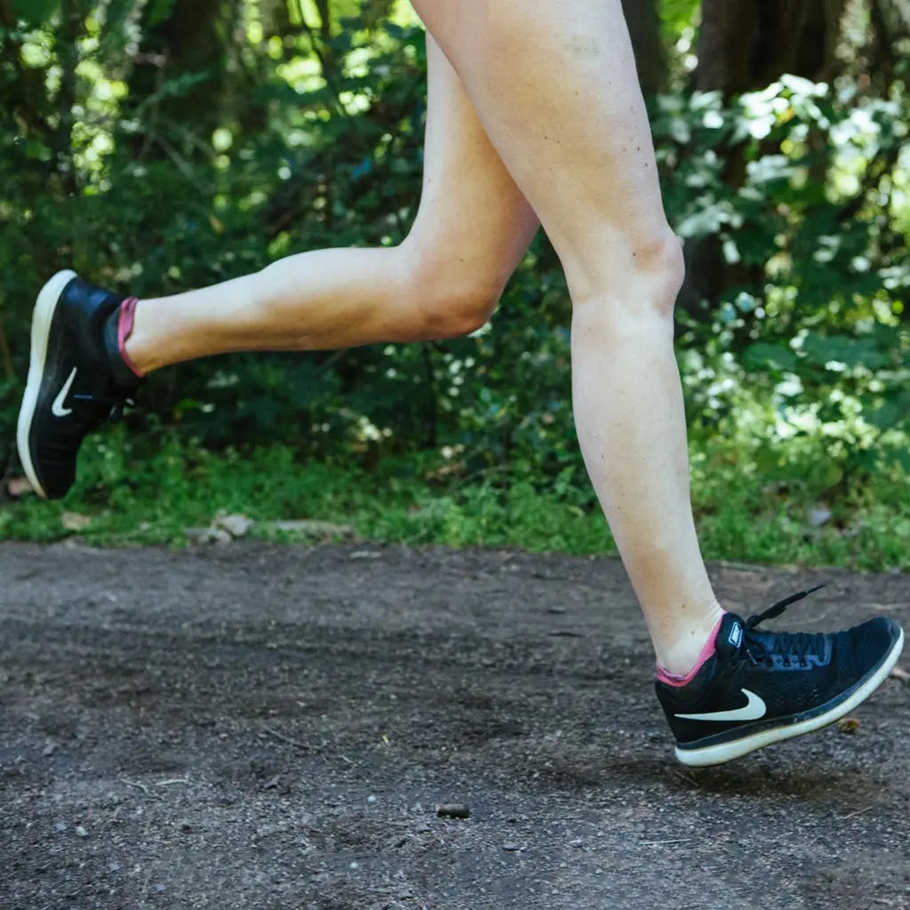 Runner wearing Cloudline merino wool running socks mid stride with both feet off the ground.