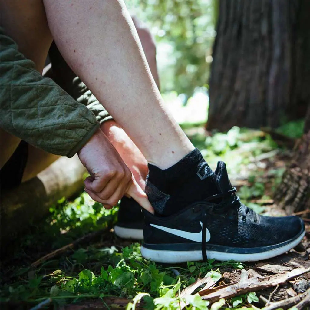 Runner wearing Cloudline merino wool socks sliding foot into running shoe.