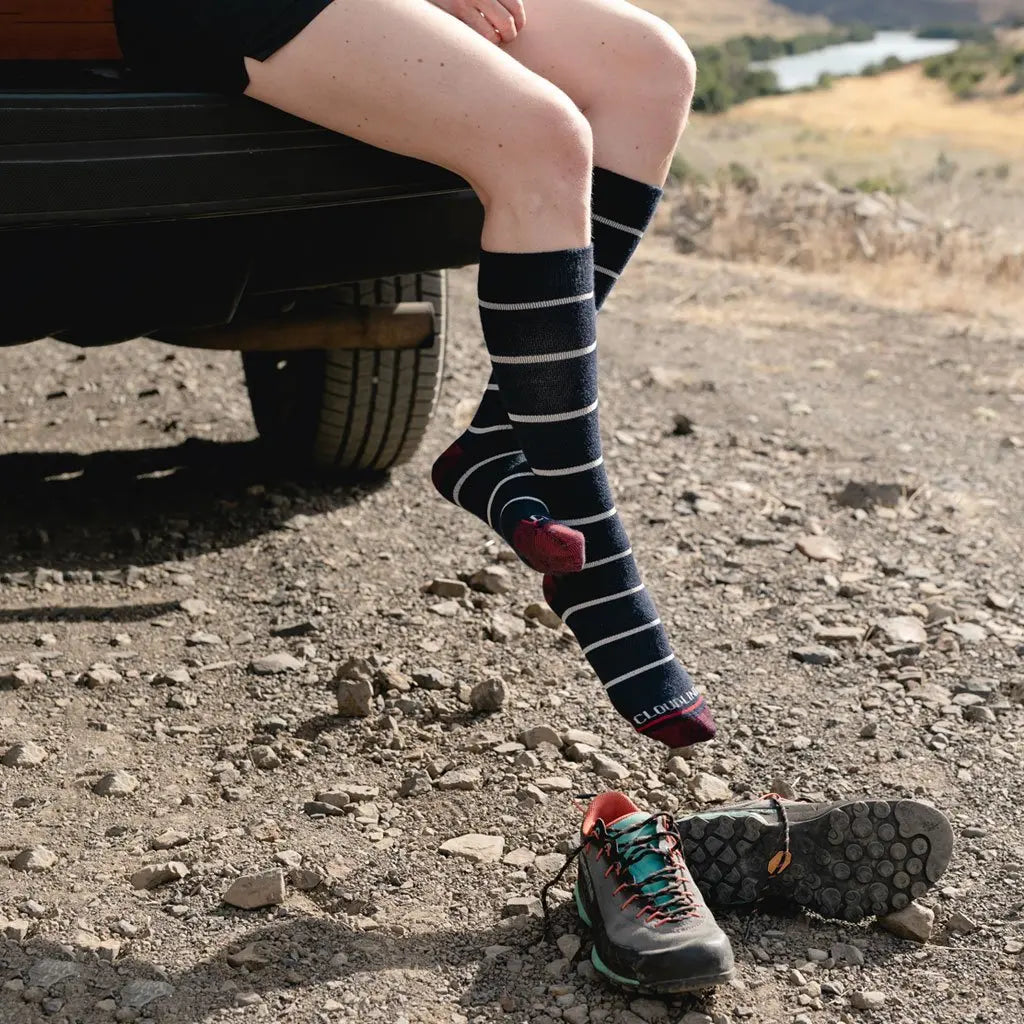 Women wearing Cloudline merino wool compression socks without shoes sitting on camper truck tailgate with feet hanging off.
