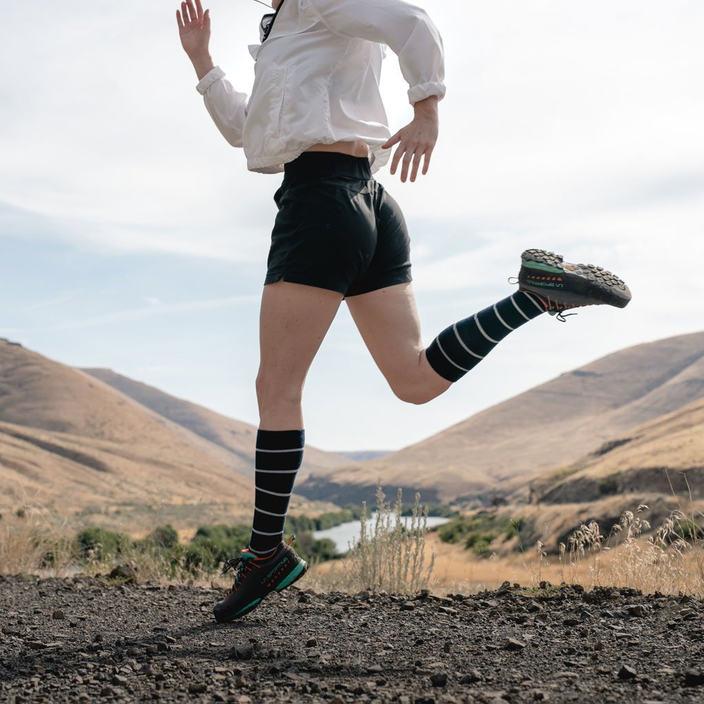 Women mid stride while trail running wearing Cloudline compression socks.