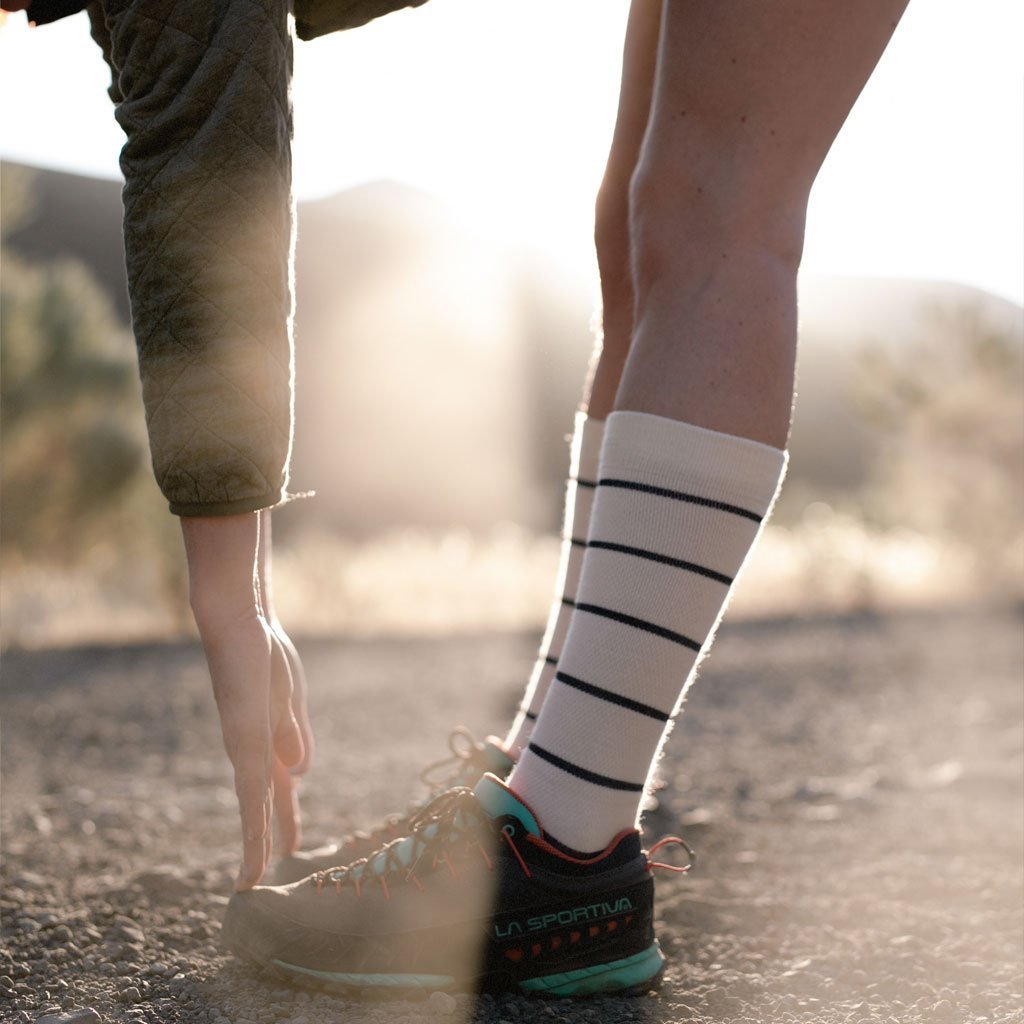 Runner wearing Cloudline compression socks stretching to touch toes before morning run.